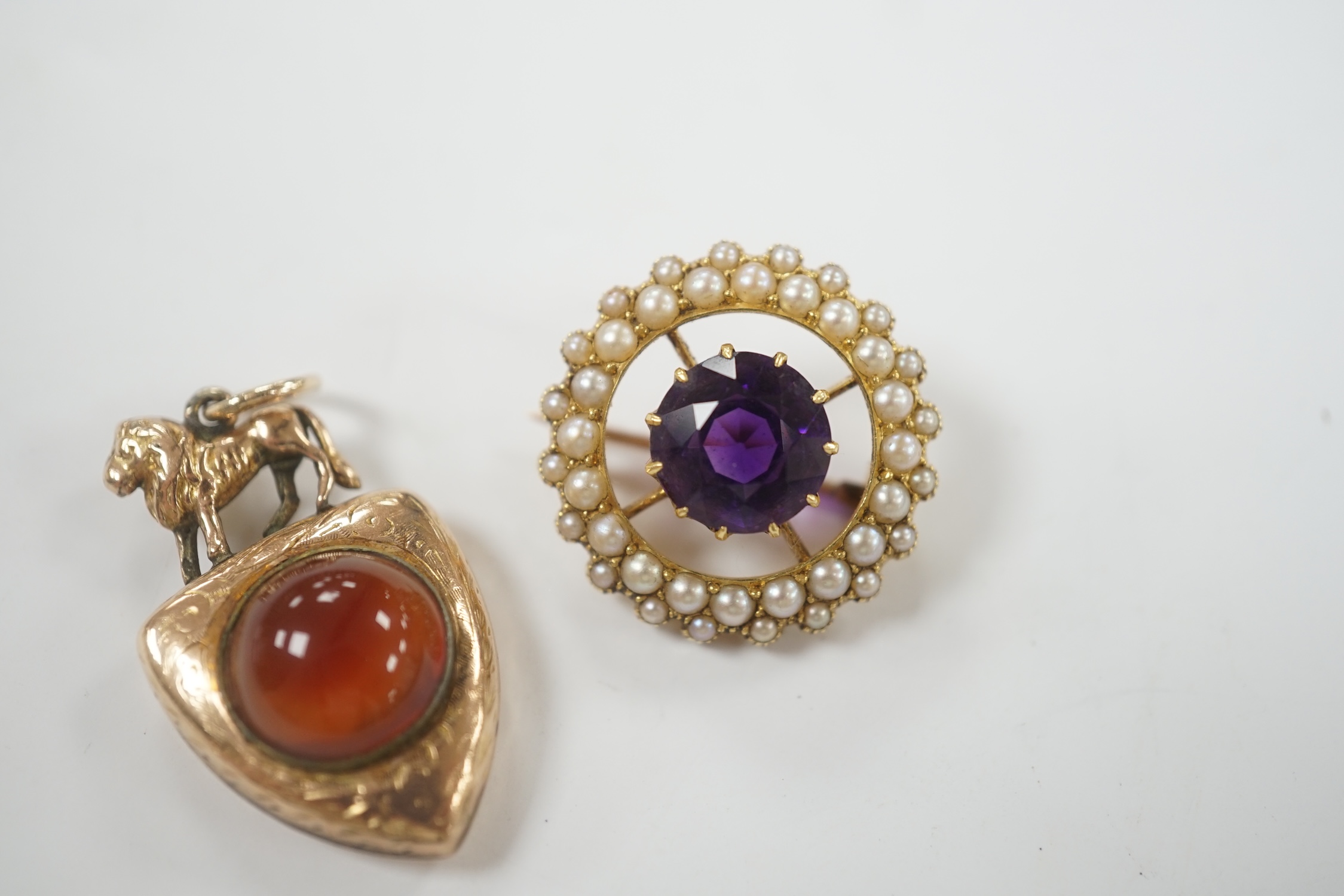 A Victorian yellow metal and two sided chalcedony set shield shaped pendant, with lion surmount, 31mm, together with an early 20th century yellow metal, amethyst and split pearl set circular brooch.